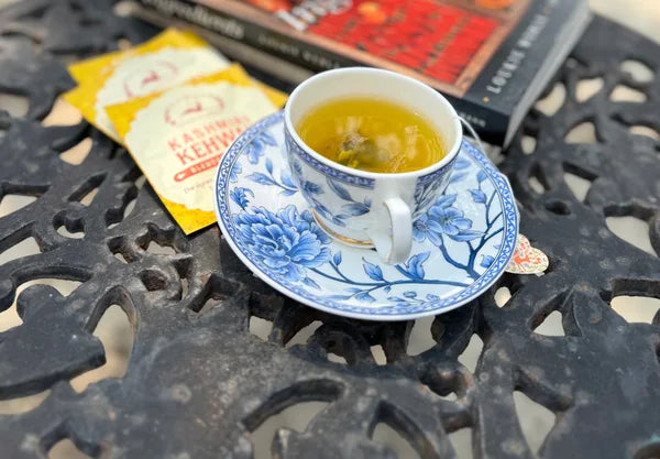 Golden Kashmiri Kehwah in a patterned cup beside its yellow sachet