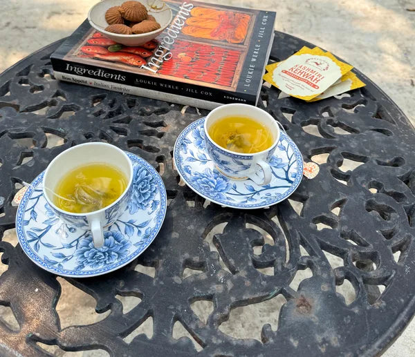 Two cups of Kashmiri Kehwah on the table with biscuits and a book