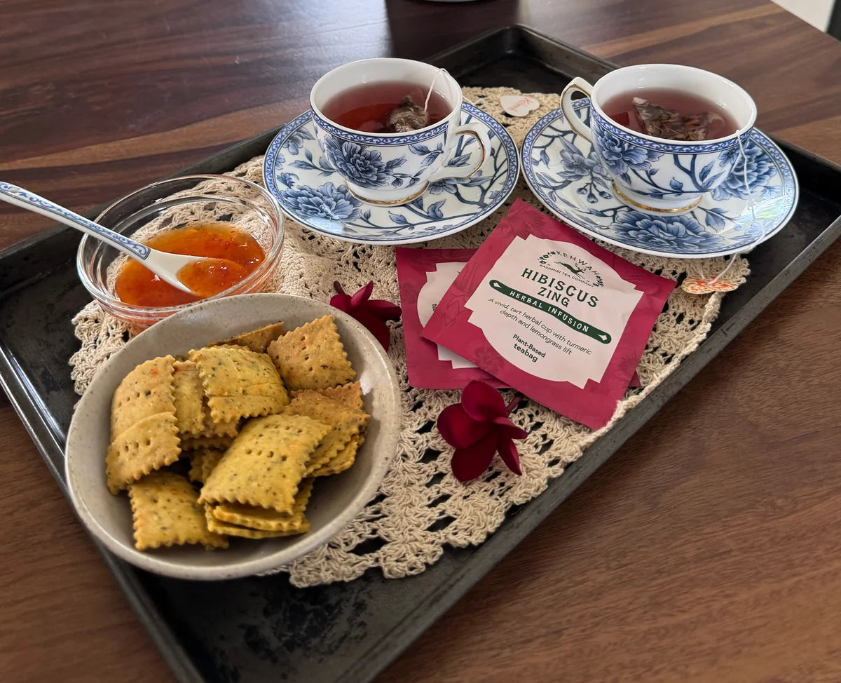 Two cups of red Hibiscus Zing with its pink sachet on a tray