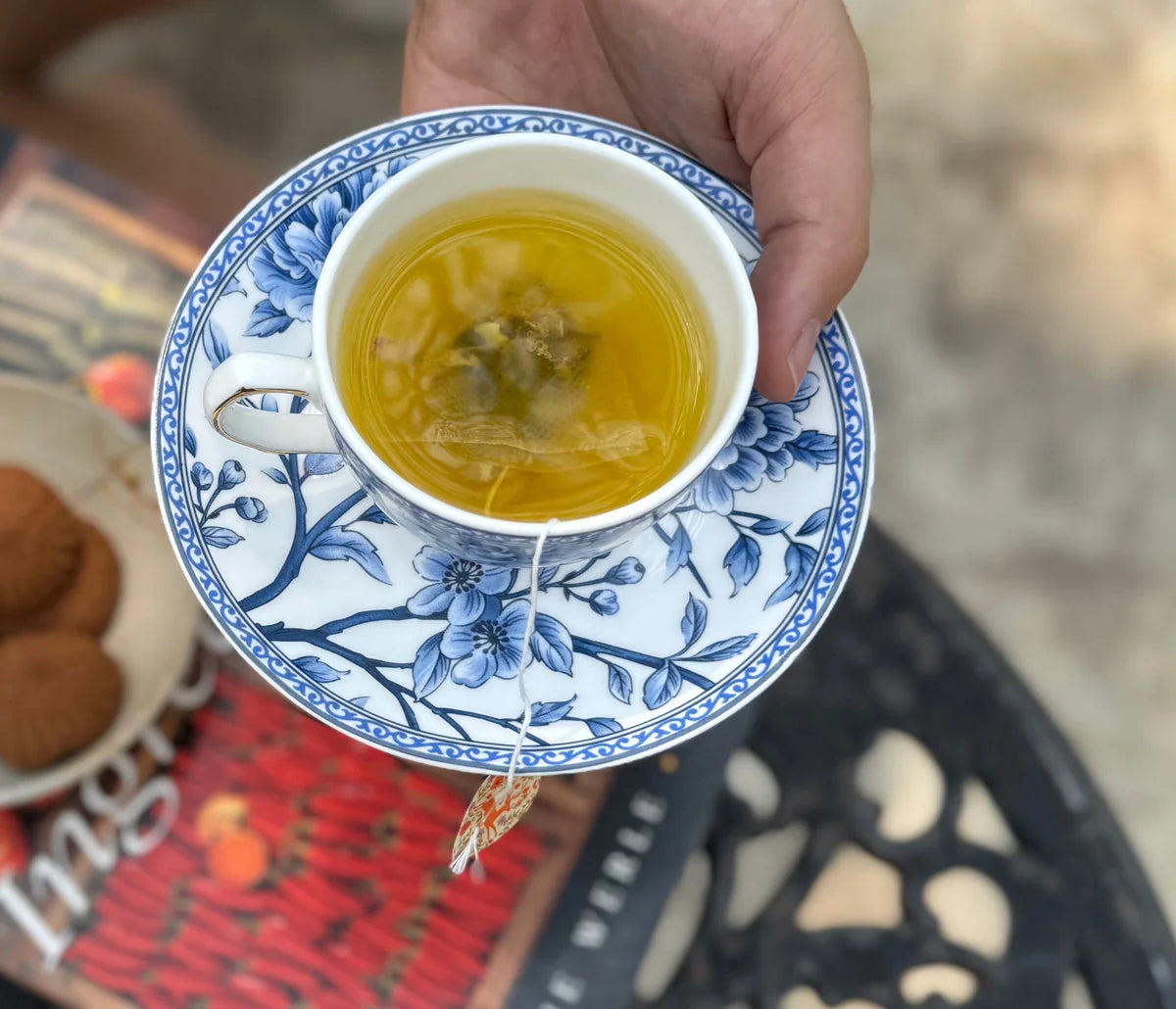 A hand holding a cup of golden Kashmiri Kehwah