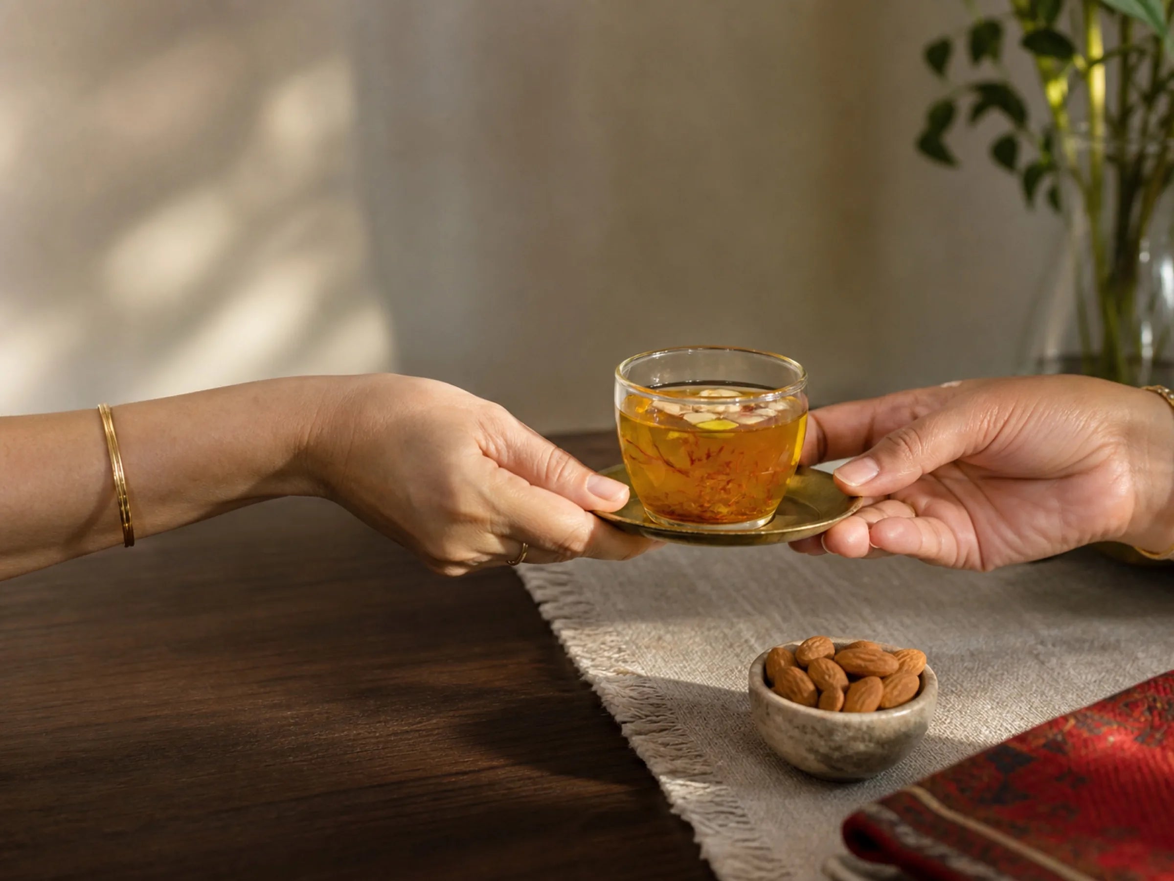 A clear cup of Kehwah being offered from host to guest