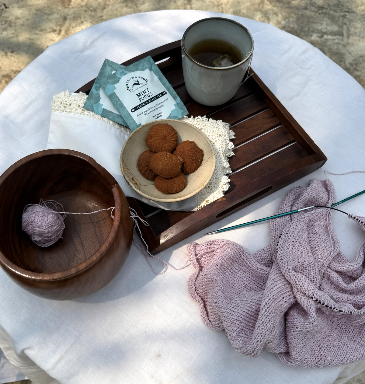 Mint Focus in a mug beside its sachet, biscuits and knitting