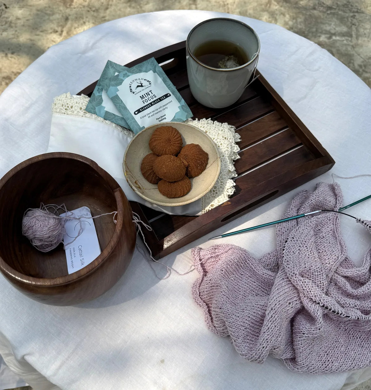 Mint Focus in a mug beside its sachet, biscuits and knitting