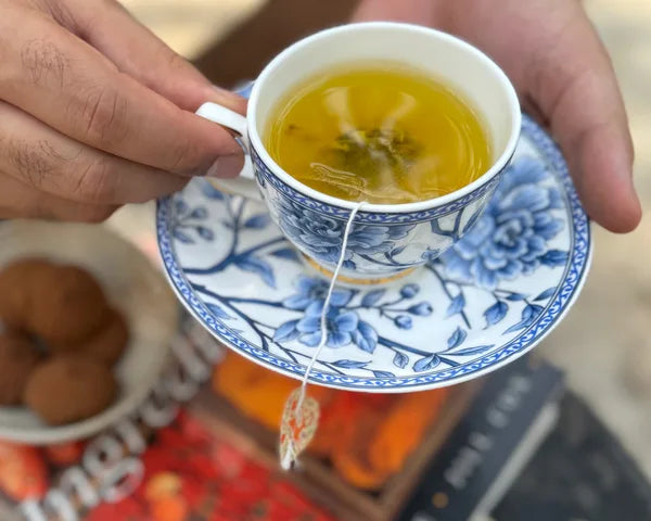 A hand holding a freshly brewed cup of golden Kashmiri Kehwah