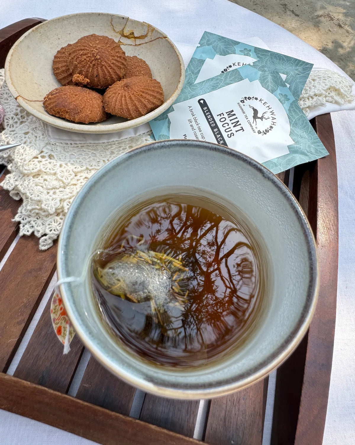 Mint Focus in a pale cup beside biscuits and its turquoise sachet