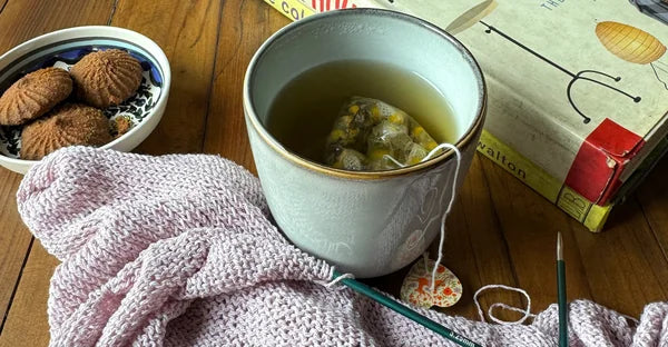 A mug of Sleep Aid beside knitting on a wooden table