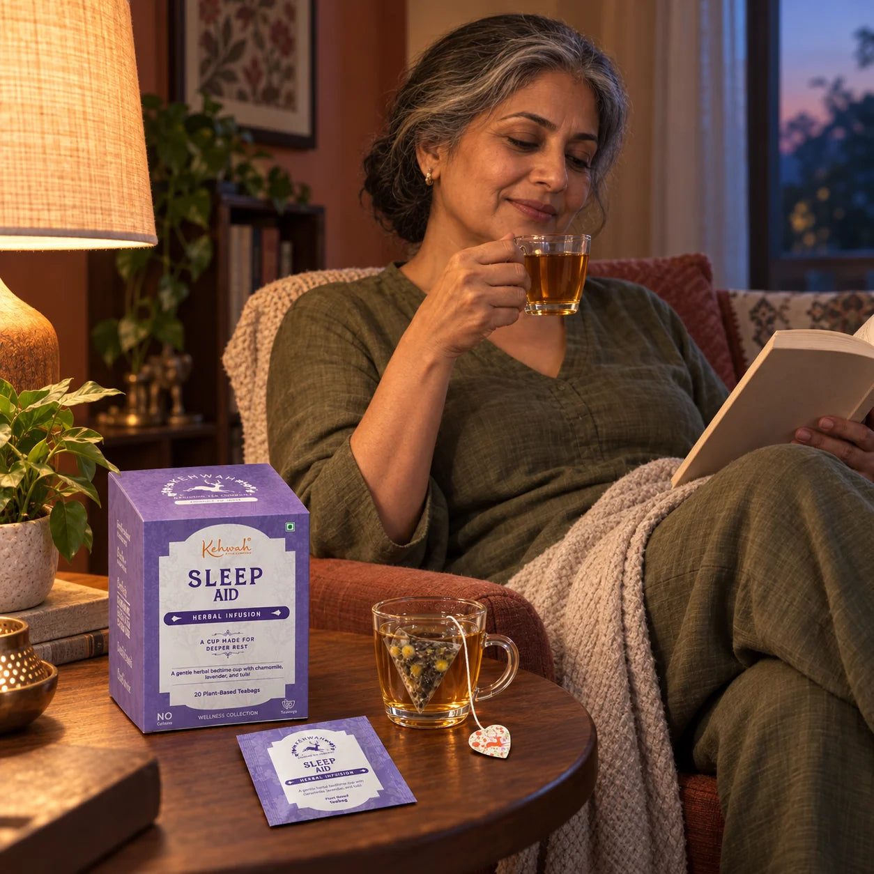 A woman with silver-streaked hair and an amber herbal cup in a reading chair.